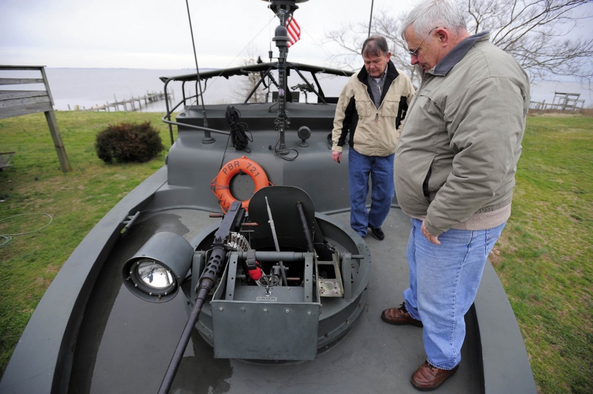 Dennis Ambruso (right) and Pat Doyle stand near the front gunner’s rig of Ambruso’s fully restored PBR 721 boat he brought down from Connecticut in his move to Currituck. The boat includes replica .50 caliber machine guns, a grenade launcher and an M-60 machine gun.